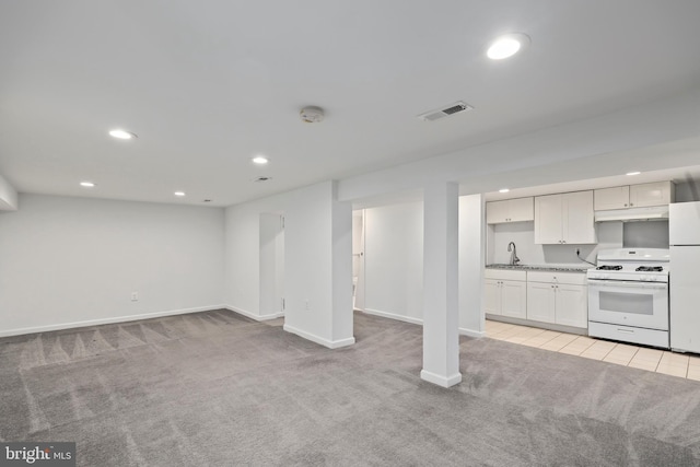 basement featuring light colored carpet, white refrigerator, and sink