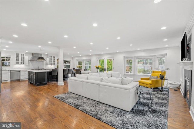 living room with hardwood / wood-style flooring, crown molding, and decorative columns