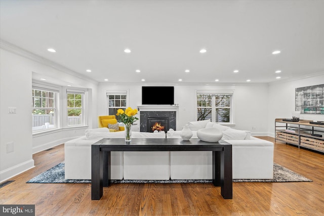 living room featuring a high end fireplace, hardwood / wood-style flooring, and ornamental molding