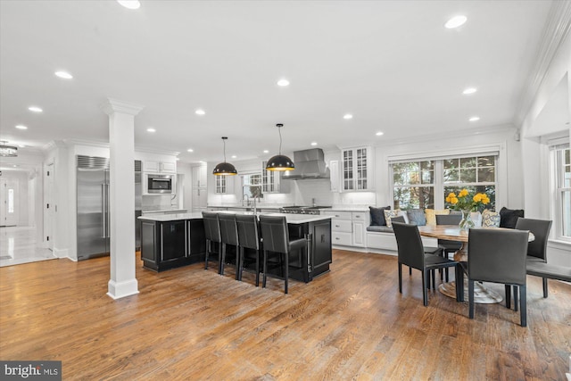 dining space featuring hardwood / wood-style flooring, decorative columns, and ornamental molding