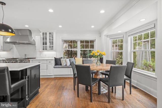 dining room featuring wood-type flooring, ornamental molding, and a wealth of natural light