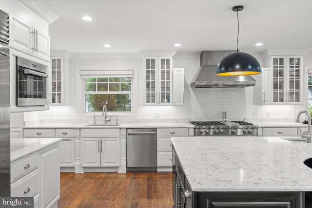 kitchen featuring sink, wall chimney exhaust hood, dark wood-type flooring, white cabinetry, and appliances with stainless steel finishes