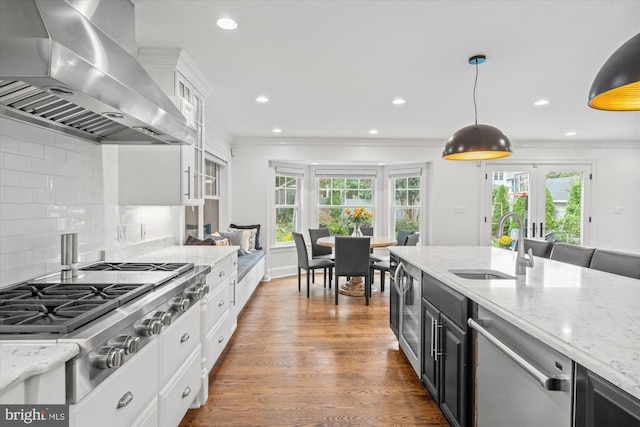 kitchen featuring wall chimney exhaust hood, plenty of natural light, hanging light fixtures, and stainless steel appliances