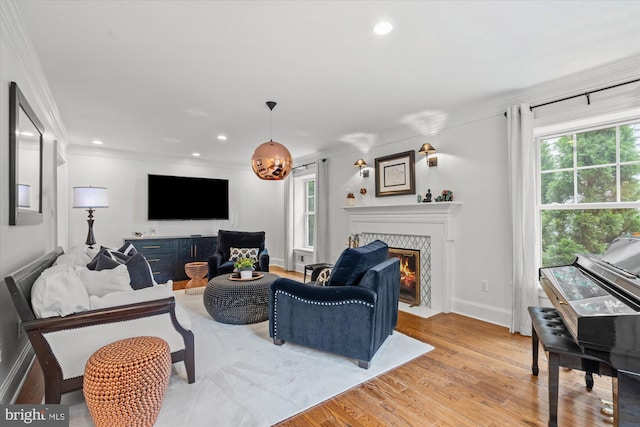 living room with ornamental molding, light wood-type flooring, and a tile fireplace