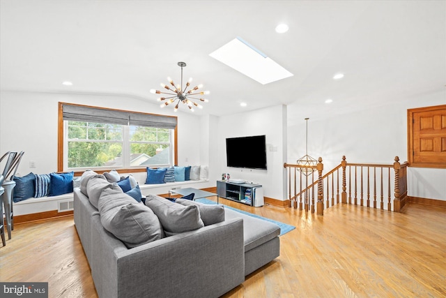 living room featuring lofted ceiling with skylight, a chandelier, and light hardwood / wood-style floors