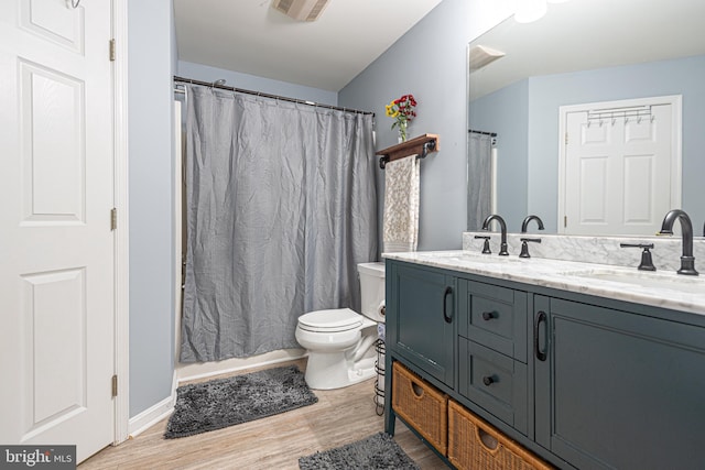 bathroom with wood-type flooring, vanity, toilet, and curtained shower