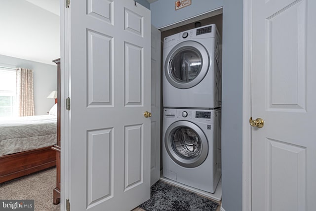 laundry area featuring stacked washer and dryer and carpet flooring