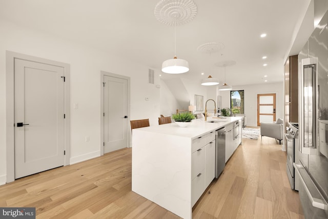 kitchen with pendant lighting, white cabinets, a center island with sink, sink, and stainless steel appliances