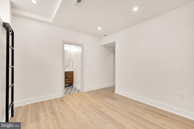 unfurnished bedroom with light wood-type flooring and ensuite bathroom