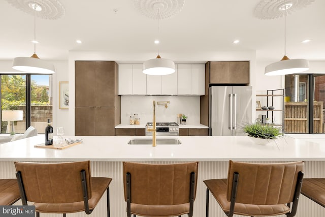 kitchen featuring an island with sink, hanging light fixtures, white cabinets, and stainless steel appliances