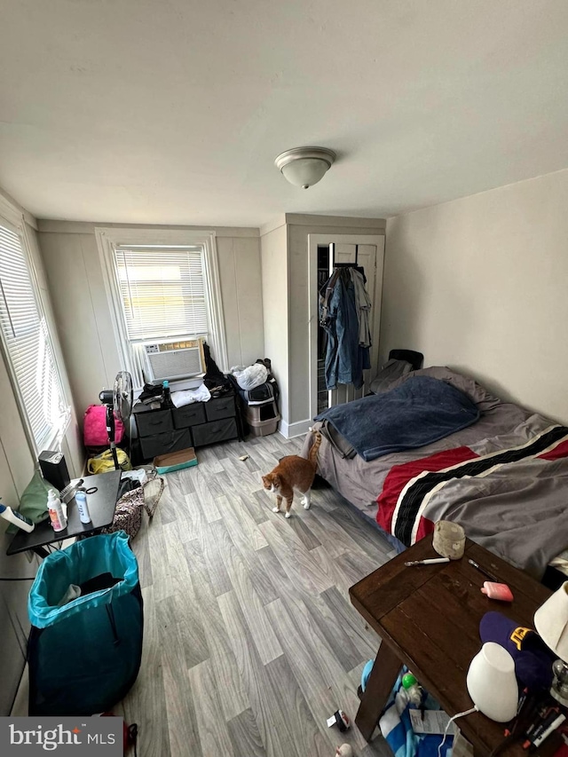 bedroom featuring light hardwood / wood-style flooring, cooling unit, and a closet