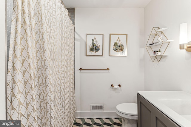 bathroom with tile patterned flooring, toilet, walk in shower, and vanity