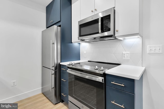 kitchen featuring blue cabinetry, stainless steel appliances, backsplash, and white cabinetry