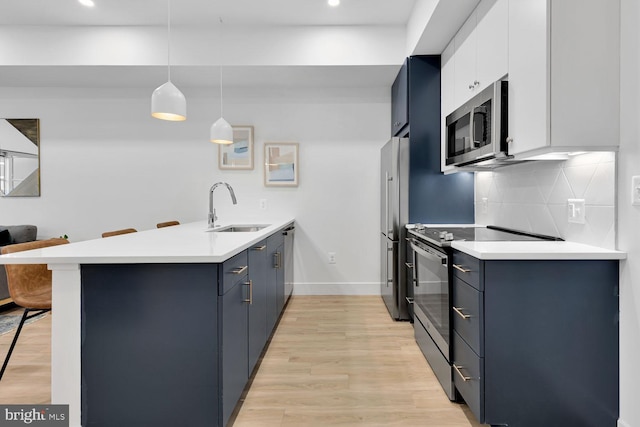 kitchen with appliances with stainless steel finishes, a kitchen breakfast bar, white cabinetry, kitchen peninsula, and decorative light fixtures