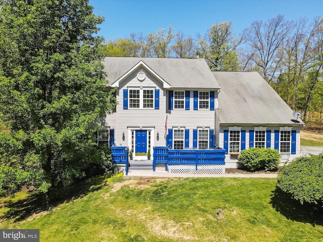 view of front facade with a wooden deck and a front lawn