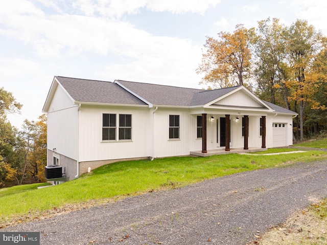 view of front facade with a porch, central air condition unit, a front yard, and a garage