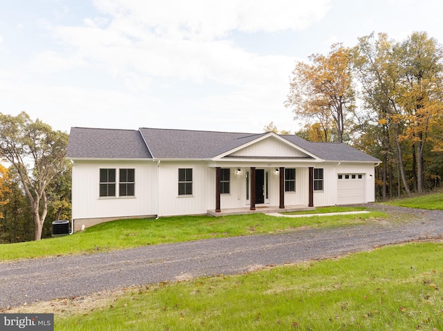 view of front of property with a front lawn, central air condition unit, covered porch, and a garage