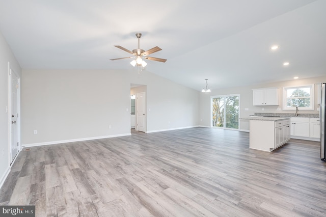 unfurnished living room with ceiling fan, light hardwood / wood-style flooring, sink, and lofted ceiling