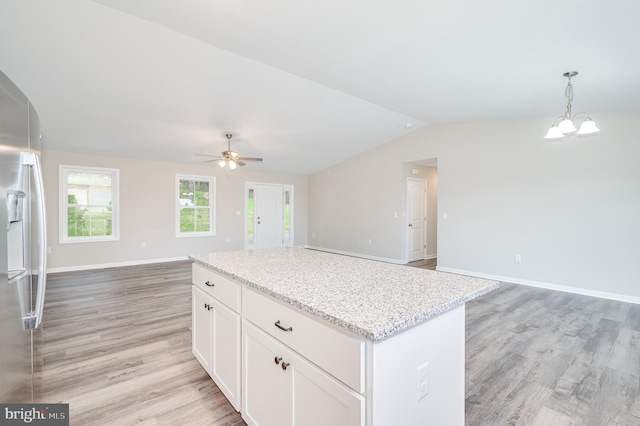 kitchen featuring pendant lighting, lofted ceiling, a kitchen island, light hardwood / wood-style flooring, and white cabinetry