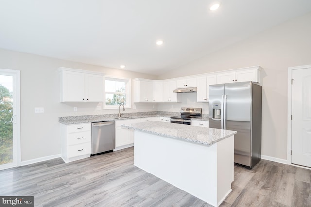 kitchen featuring white cabinets, vaulted ceiling, stainless steel appliances, a center island, and light hardwood / wood-style floors