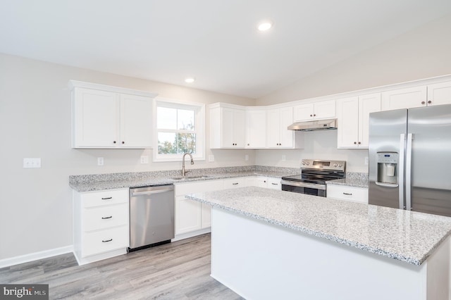 kitchen with lofted ceiling, light stone counters, stainless steel appliances, light hardwood / wood-style floors, and white cabinetry