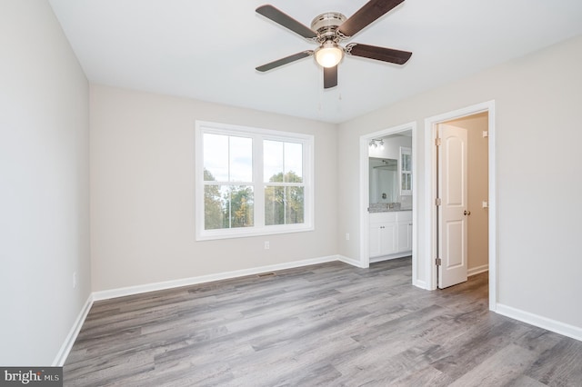 unfurnished bedroom with light wood-type flooring, ceiling fan, and connected bathroom