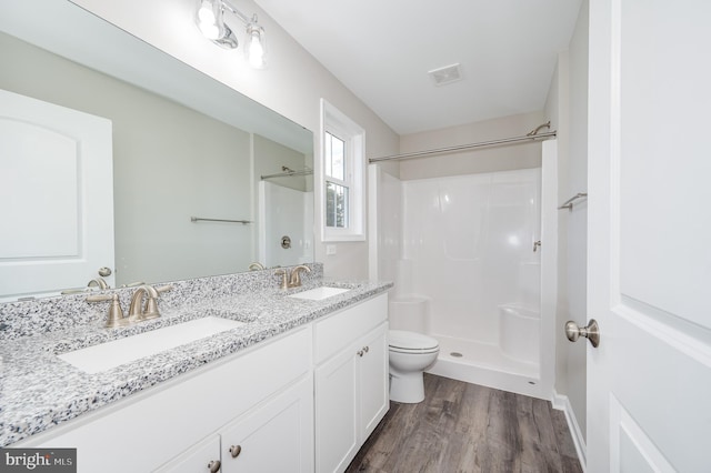 bathroom with wood-type flooring, walk in shower, vanity, and toilet