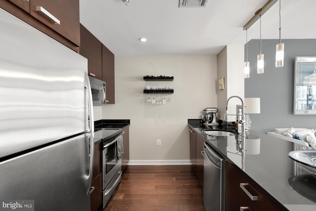 kitchen with pendant lighting, dark brown cabinetry, dark hardwood / wood-style flooring, sink, and appliances with stainless steel finishes