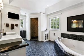 bathroom featuring ornamental molding, tiled tub, and vanity