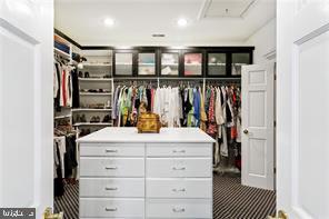 walk in closet featuring dark carpet