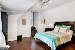 bedroom with lofted ceiling, dark hardwood / wood-style flooring, and track lighting