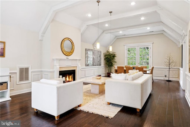 living room featuring a fireplace, dark wood finished floors, visible vents, wainscoting, and vaulted ceiling with beams