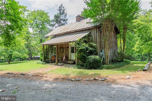 exterior space featuring a front lawn, metal roof, a standing seam roof, and a chimney
