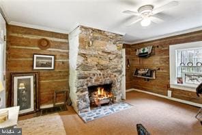 living area featuring wood walls, light colored carpet, a stone fireplace, ornamental molding, and ceiling fan