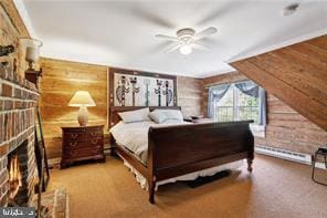 bedroom with wood walls, a baseboard heating unit, ceiling fan, and a brick fireplace