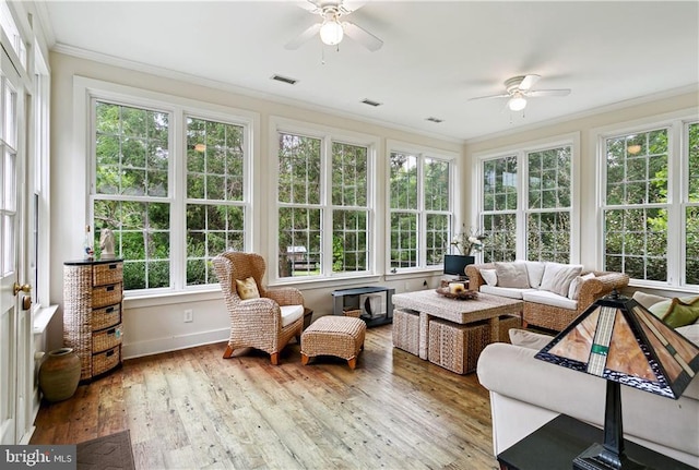 sunroom featuring crown molding, a wooden deck, wood-type flooring, and visible vents