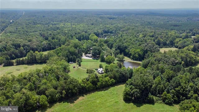 drone / aerial view with a wooded view and a water view