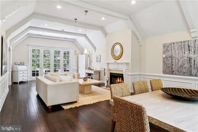 living area featuring a decorative wall, wainscoting, vaulted ceiling, dark wood-type flooring, and a premium fireplace