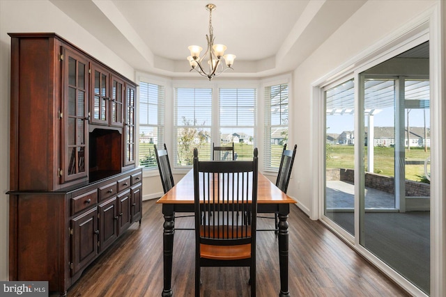 dining area featuring dark hardwood / wood-style floors, a chandelier, and a raised ceiling