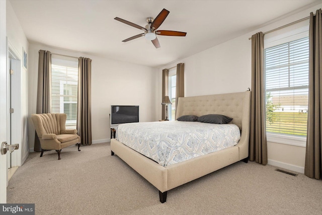 carpeted bedroom featuring multiple windows and ceiling fan