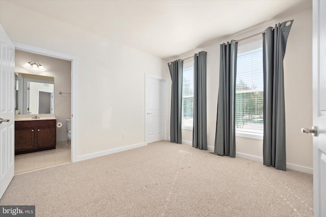 unfurnished bedroom featuring light colored carpet, ensuite bath, and sink