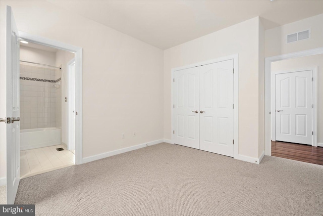 unfurnished bedroom with a closet, ensuite bath, and carpet floors