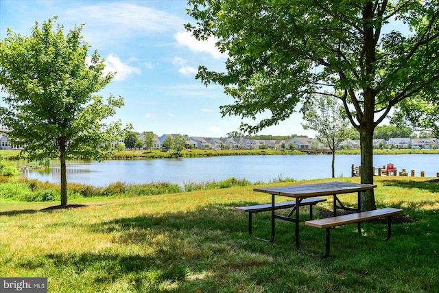 view of property's community with a water view and a lawn