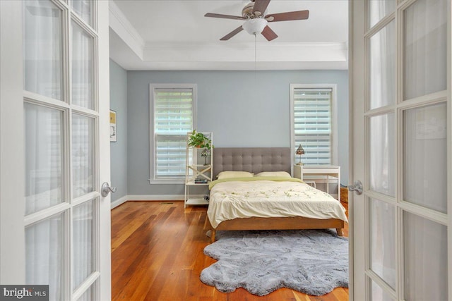 bedroom with ornamental molding, ceiling fan, hardwood / wood-style floors, and french doors