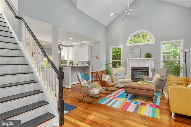 living room with ceiling fan, light hardwood / wood-style flooring, and high vaulted ceiling