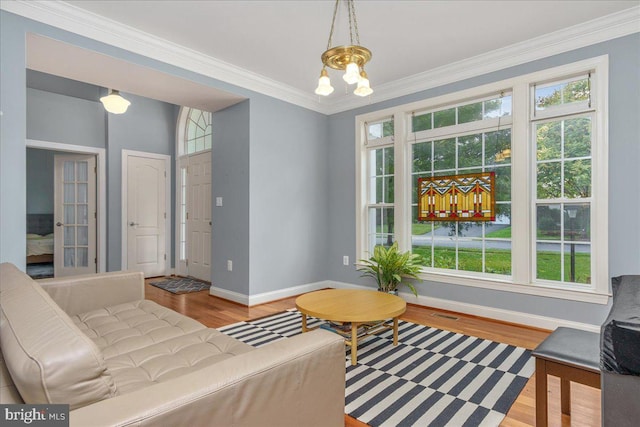 sitting room featuring light wood-type flooring, a chandelier, and crown molding