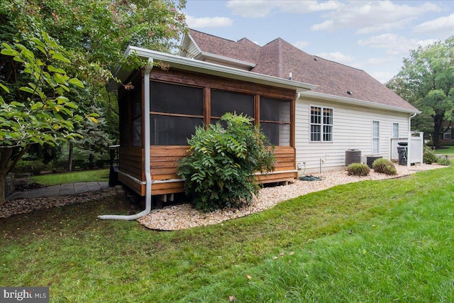 back of property featuring a lawn, a sunroom, and central air condition unit