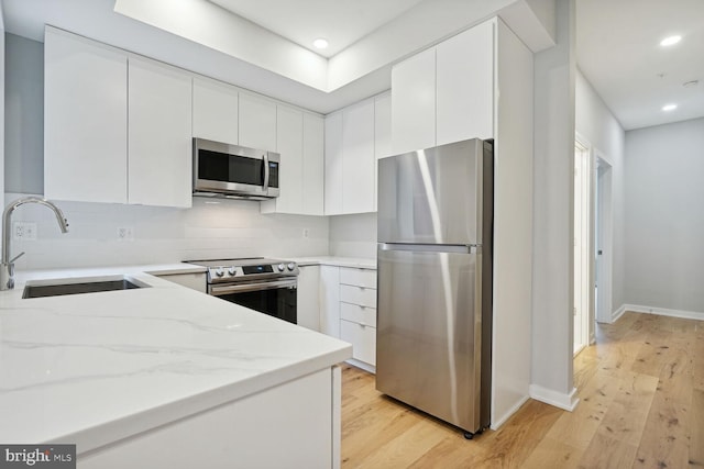 kitchen featuring light stone countertops, appliances with stainless steel finishes, white cabinetry, tasteful backsplash, and sink