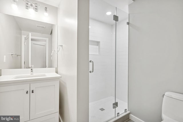 bathroom with a shower with shower door, vanity, and toilet