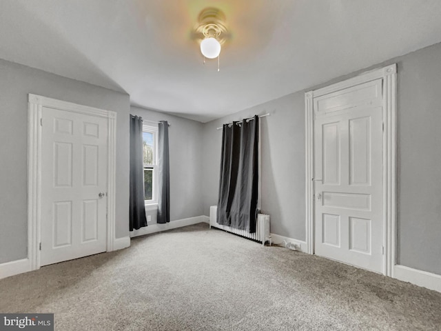 unfurnished bedroom with ceiling fan, radiator heating unit, and carpet flooring